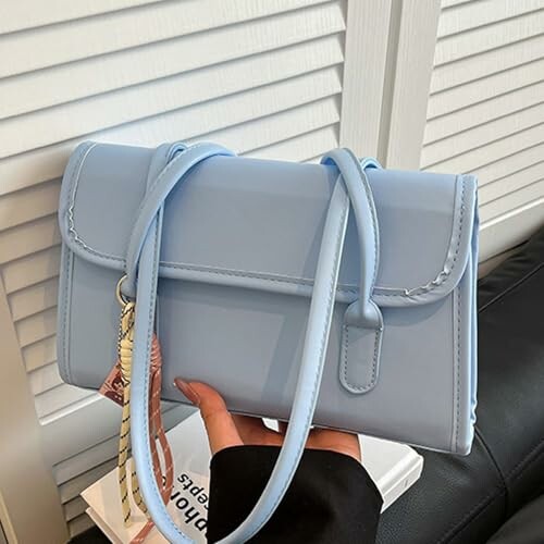 Sac à main bleu clair tenu par une personne.