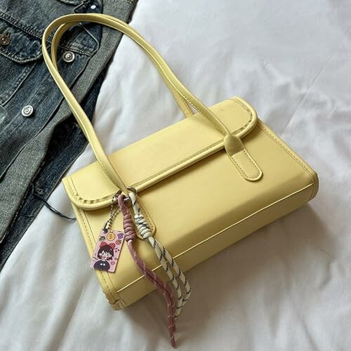 Sac à main jaune sur un lit avec des porte-clés.